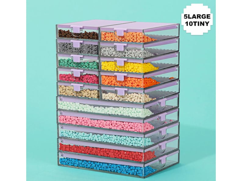 May include: Stack of clear plastic storage containers with lavender lids and handles, filled with colorful beads. The containers are labeled "5 LARGE 10 TINY". The beads are in various colors, including brown, gray, green, pink, blue, and red.