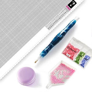 Peut inclure: Kit de peinture diamant avec une toile blanche, un outil stylo bleu, un plateau avec des perles roses et trois sachets de perles étiquetés "Cateared", "rouge" et "rouge".