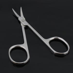 May include: A pair of silver-toned cuticle scissors with sharp pointed tips. The scissors have a small, round hole in the center of the handle.