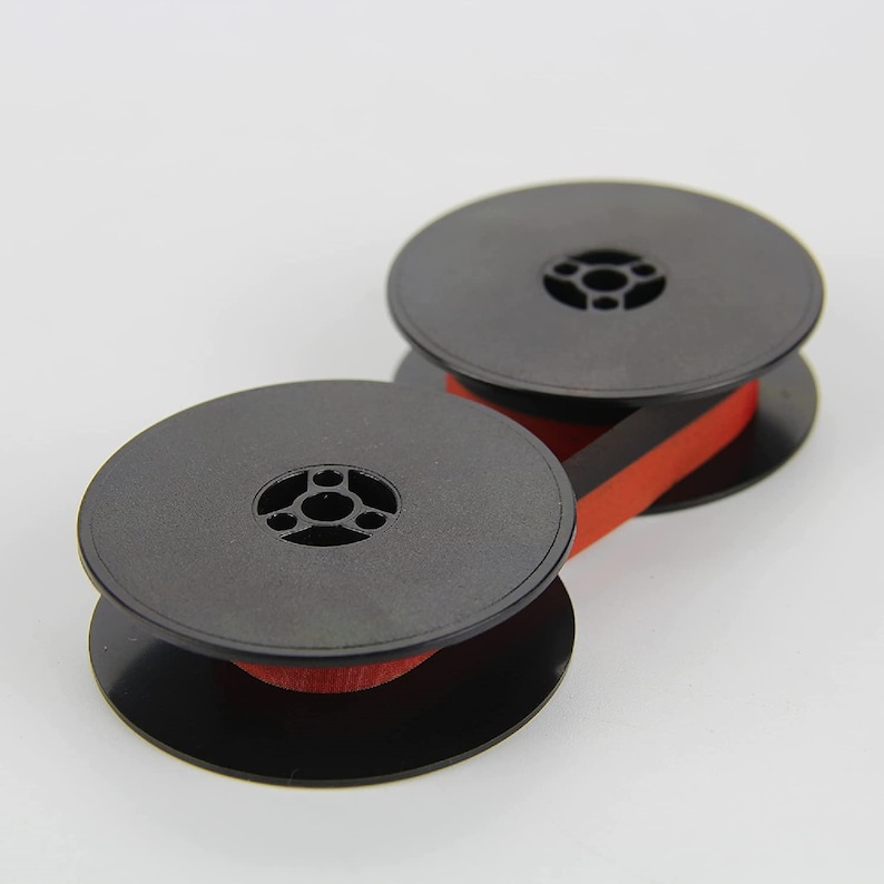 May include: Two black spools with red ribbon, used for a typewriter.