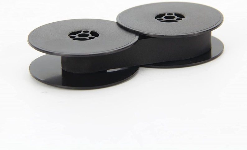 May include: Two black plastic spools for typewriter ribbon, connected by a black ribbon.