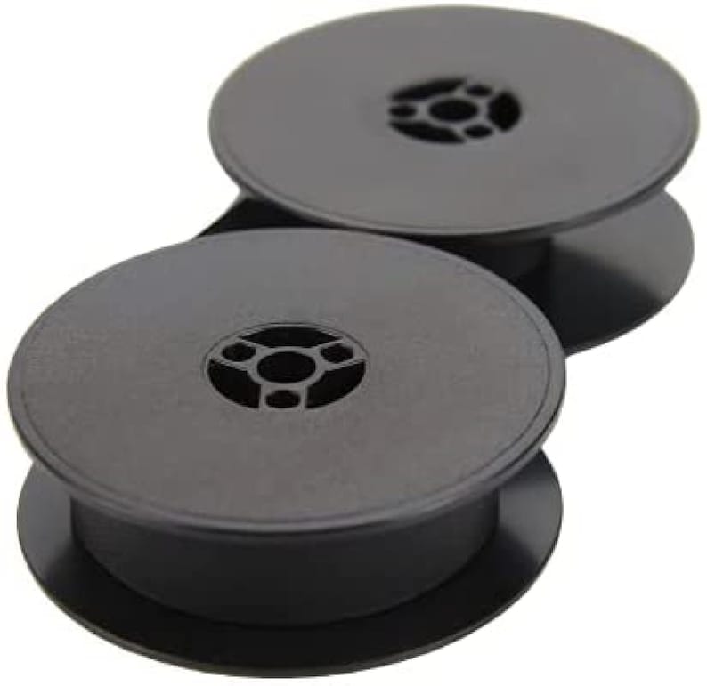May include: Two black typewriter ribbon spools. Each spool has a center hole with three spokes.