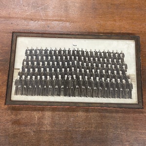 May include: Black and white photograph of a group of men in uniform, likely sailors, standing in formation. The photo is framed and includes the text "U.S.A." and "NAVAL TRAINING CENTER - GREAT LAKES, ILL. - MARCH 1918".