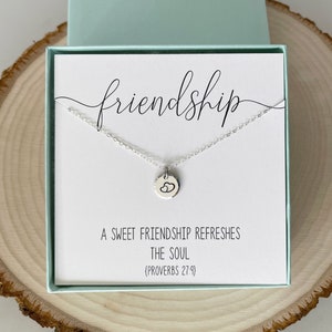 May include: A silver necklace with a small charm that says "friendship" and has two hearts on it. The necklace is in a white box with a card that says "A sweet friendship refreshes the soul (Proverbs 27:9)"
