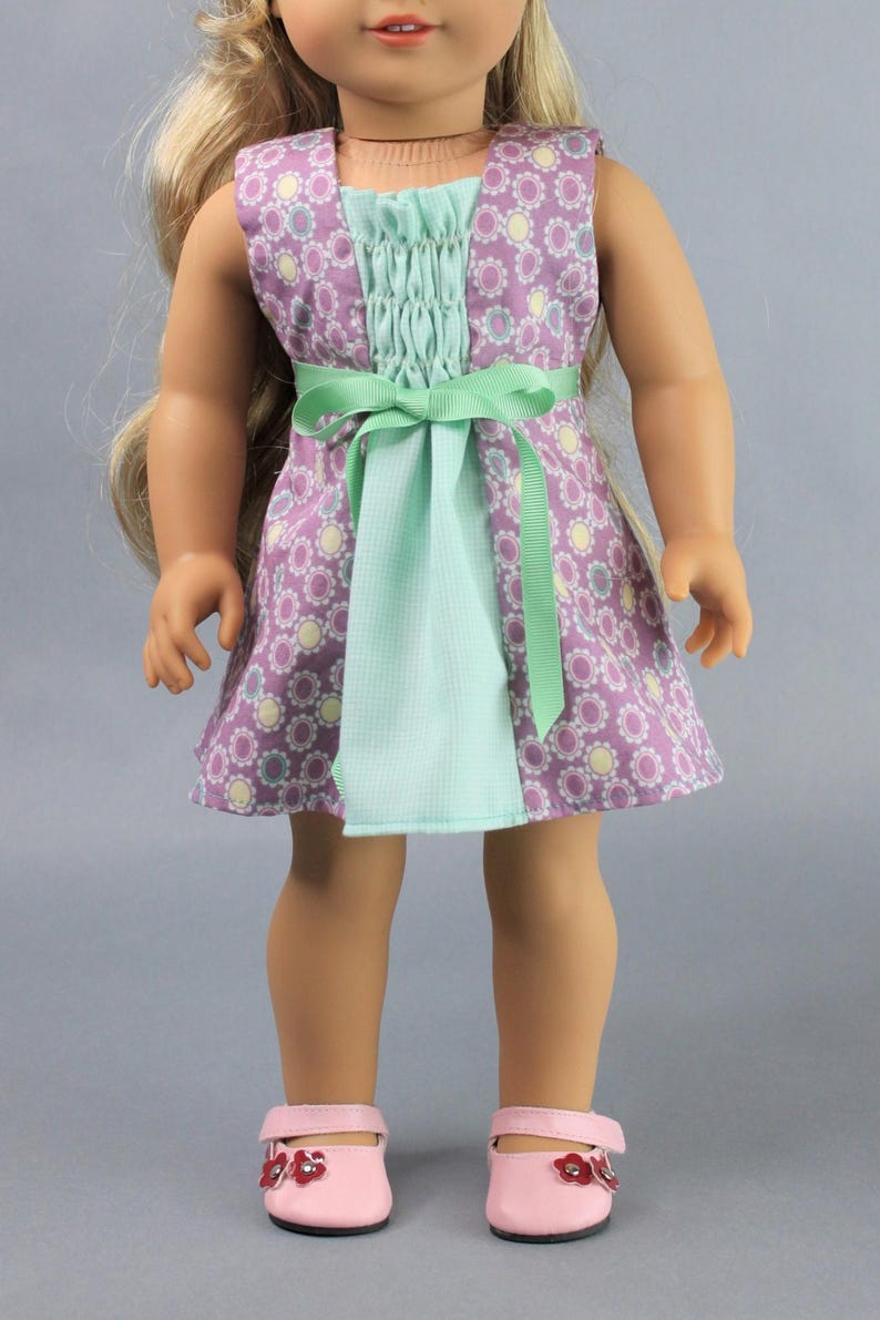 This 18 inch doll Shirred Front Dress PDF Sewing pattern is styled from the 1970s. This dress has a center front panel with shirring in the bodice extends to the skirt. There are two options for shirring in the center front panel. You may sew gathers and then apply a ⅛ to ¼ inch ribbon or gather the front section with elastic for a smocked effect. There are two sleeve options for the dress: a puff sleeve option or sleeveless. The neckline on dress is square and the skirt is semi-full.