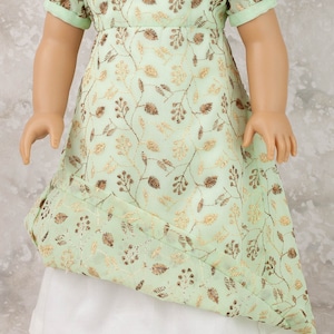 May include: A mint green doll dress with gold embroidered floral patterns. The dress features short sleeves, a square neckline, and a white underskirt. A gold-toned necklace is visible.