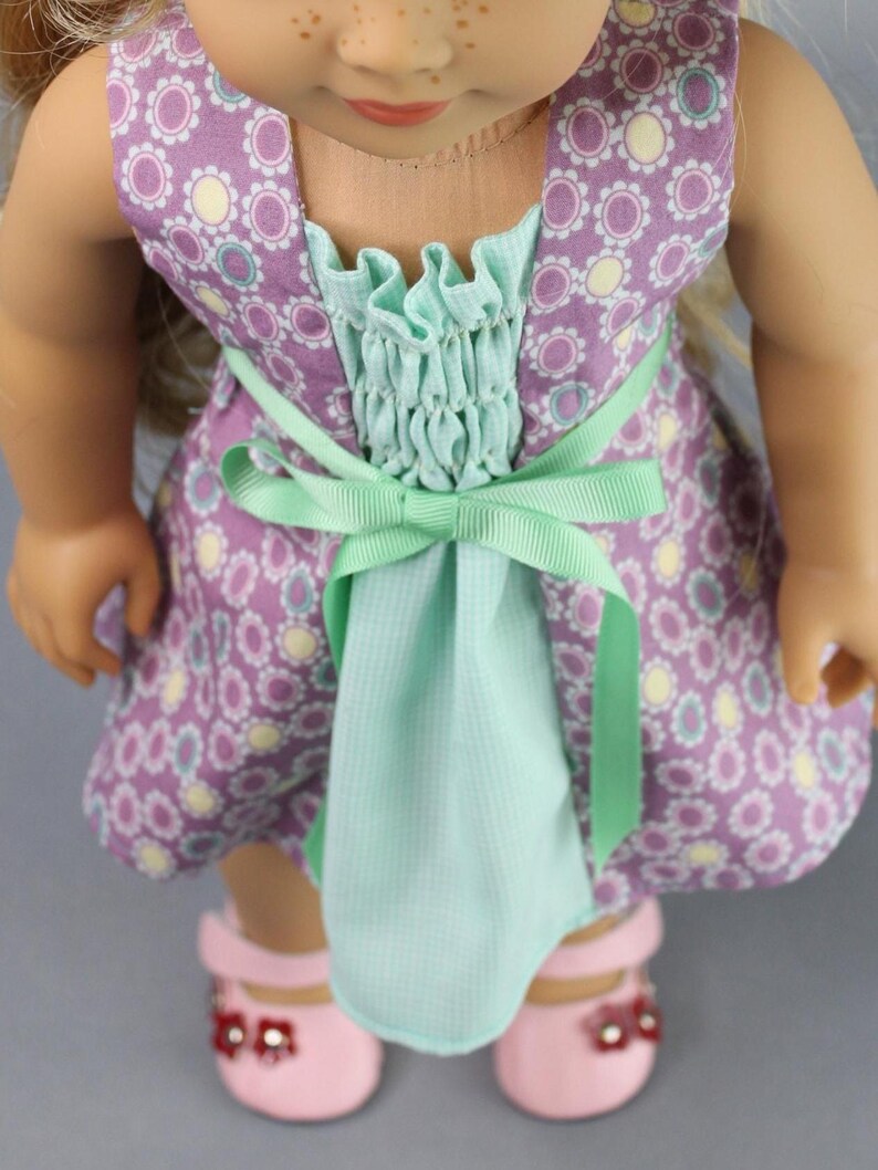 This 18 inch doll Shirred Front Dress PDF Sewing pattern is styled from the 1970s. This dress has a center front panel with shirring in the bodice extends to the skirt. There are two options for shirring in the center front panel. You may sew gathers and then apply a ⅛ to ¼ inch ribbon or gather the front section with elastic for a smocked effect. There are two sleeve options for the dress: a puff sleeve option or sleeveless. The neckline on dress is square and the skirt is semi-full.
