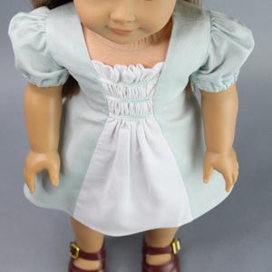 This 18 inch doll Shirred Front Dress PDF Sewing pattern is styled from the 1970s. This dress has a center front panel with shirring in the bodice extends to the skirt. There are two options for shirring in the center front panel. You may sew gathers and then apply a ⅛ to ¼ inch ribbon or gather the front section with elastic for a smocked effect. There are two sleeve options for the dress: a puff sleeve option or sleeveless. The neckline on dress is square and the skirt is semi-full.
