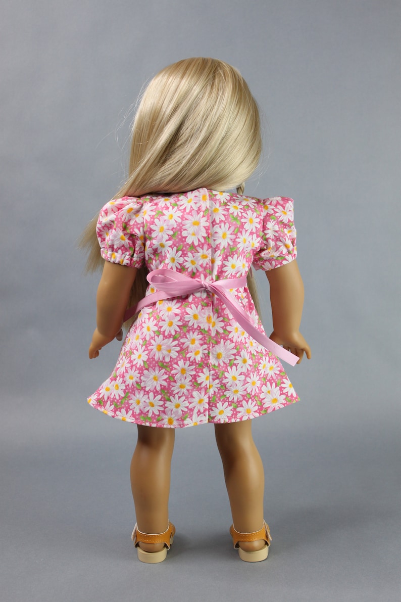 This 18 inch doll Shirred Front Dress PDF Sewing pattern is styled from the 1970s. This dress has a center front panel with shirring in the bodice extends to the skirt. There are two options for shirring in the center front panel. You may sew gathers and then apply a ⅛ to ¼ inch ribbon or gather the front section with elastic for a smocked effect. There are two sleeve options for the dress: a puff sleeve option or sleeveless. The neckline on dress is square and the skirt is semi-full.