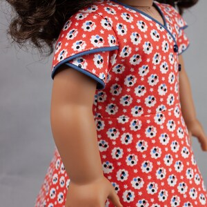 May include: A red and white floral dress with blue trim. The dress has short sleeves and a V-neck.