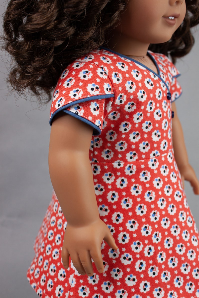 May include: A red and white floral dress with blue trim. The dress has short sleeves and a V-neck.