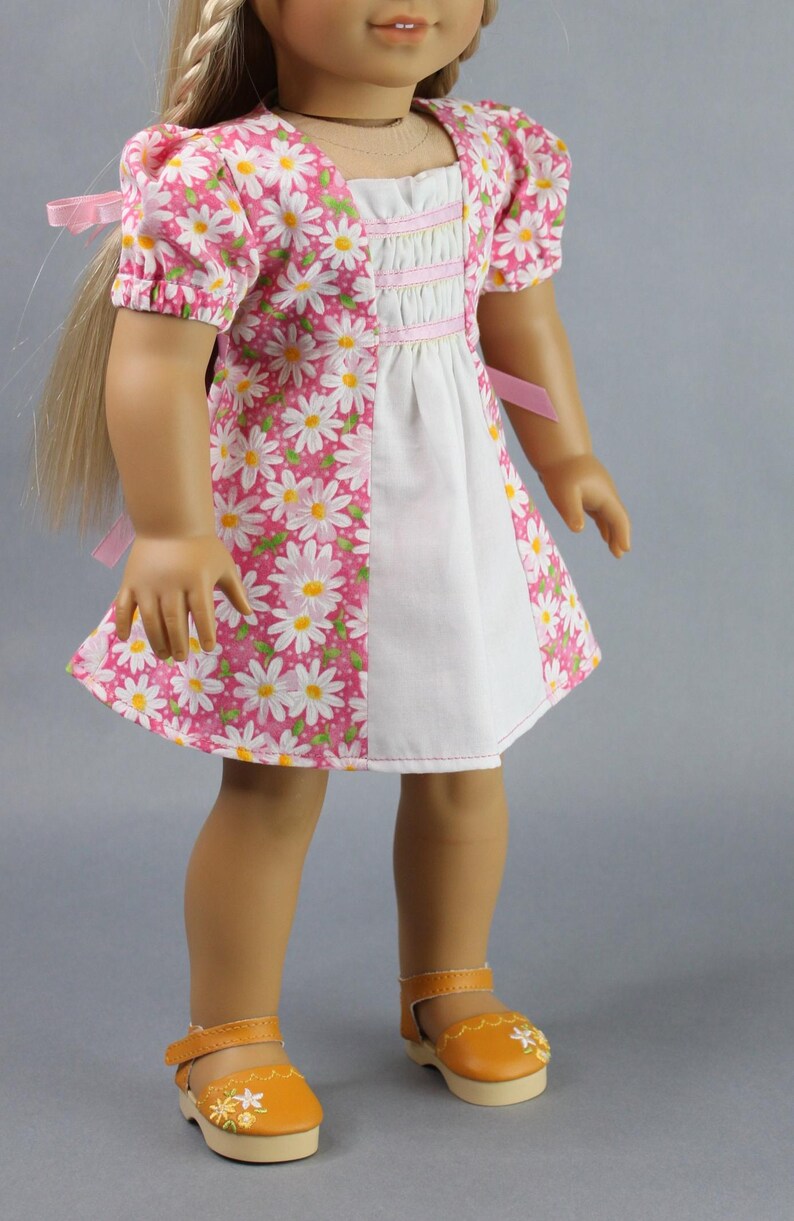 This 18 inch doll Shirred Front Dress PDF Sewing pattern is styled from the 1970s. This dress has a center front panel with shirring in the bodice extends to the skirt. There are two options for shirring in the center front panel. You may sew gathers and then apply a ⅛ to ¼ inch ribbon or gather the front section with elastic for a smocked effect. There are two sleeve options for the dress: a puff sleeve option or sleeveless. The neckline on dress is square and the skirt is semi-full.