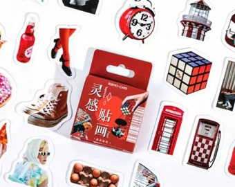 May include: A set of colorful stickers featuring various images, including a red alarm clock, a red telephone booth, a red gas pump, a Rubik's cube, a lighthouse, a donut, a pair of sneakers, a carton of eggs, and a woman wearing a hat and sunglasses. The stickers are packaged in a red box with Chinese characters that translate to "Special Edition".