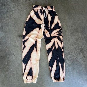 Może przedstawiać: Czarno-białe spodnie dresowe tie-dye z wzorem spiralnym.