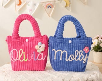 May include: Two corduroy tote bags with top handles and snap closures. The hot pink bag features the name Olivia in white script with a multi-coloured flower accent. The blue bag features the name Molly in white script with a pink flower accent.
