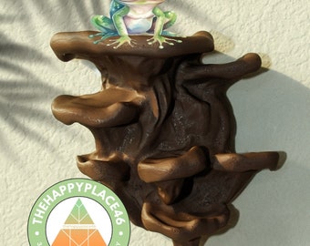 May include: A brown 3D printed mushroom-shaped wall mount with three shelves. A green tree frog sits on the top shelf. The wall mount is labeled "The Happy Place 46 3D Print Factory".