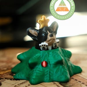 May include: A 3D-printed Christmas tree ornament featuring a black and white Chihuahua wearing a gold star crown. The green tree has a red ornament. The Happy Place 46 logo is in the background.