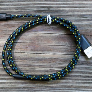 May include: A black braided USB charging cable with yellow and blue accents. The cable is coiled and has a micro USB connector on one end and a standard USB connector on the other end.