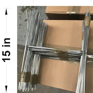 May include: Bundled metal sign stakes, each measuring 15 inches (38 cm) in height and 10 inches (25 cm) in width. The stakes are silver and bundled together with tape, resting on a cardboard box.