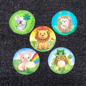 May include: Five round stickers with a green shamrock theme. Each sticker features a different animal: a koala, a lion, a hedgehog, a pig, and an owl. The stickers have a white background with green shamrocks and the text "Lucky" on the koala sticker.