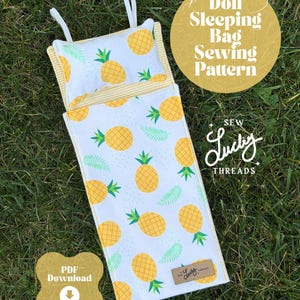 Könnte beinhalten: Ein Schnittmuster für einen Puppen-Schlafsack mit weißem Hintergrund und gelben Ananas und grünen Blättern. Das Kissen und der Schlafsack haben einen gelb gestreiften Rand. Der Text "Doll Sleeping Bag Sewing Pattern" befindet sich in einem goldenen Kreis.