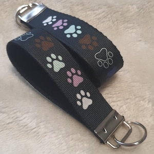 May include: Black key chain with a silver key ring and a black ribbon with paw prints in white, pink, and brown.