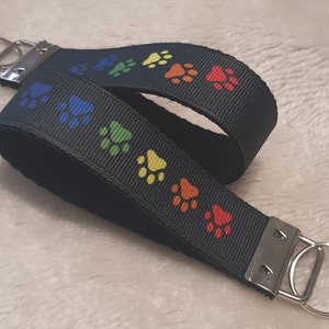 May include: Black key chain with a rainbow paw print design. The key chain has two silver key rings.