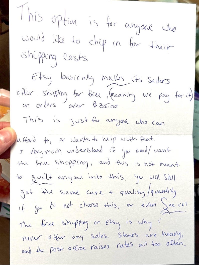 May include: Handwritten note with text about Etsy shipping costs. The note explains the option to contribute to shipping fees, the free shipping policy for orders over $35, and the reasons for not offering sales due to shipping costs.