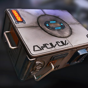 May include: A gray metal box with a handle and a circular panel on the top. The box has a label that says "D'Q'L'K" and a small logo that looks like a rebel alliance symbol. The box has a red light that says "LOCK"