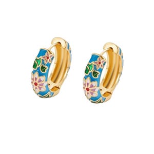 May include: A pair of gold-colored hoop earrings with a blue enamel floral design. The earrings feature a gold-colored interior and are decorated with pink, red, and green floral accents. The earrings are shown against a white background.
