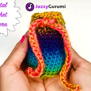 May include: A rainbow crochet drawstring pouch with a yellow, pink, and orange braided cord. The pouch is held in a person's hands. "Digital Crochet Pattern" and "JazzyGurumi" are written in the background.