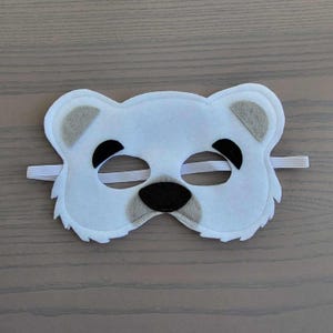 May include: White felt polar bear mask with black eyes, nose, and mouth. The mask has elastic straps for wearing.
