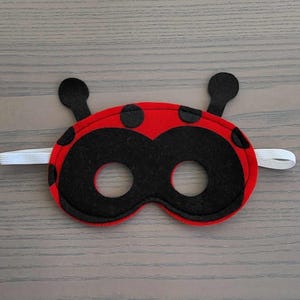 May include: Red felt ladybug mask with black spots and eye holes. The mask has an elastic band for wearing.