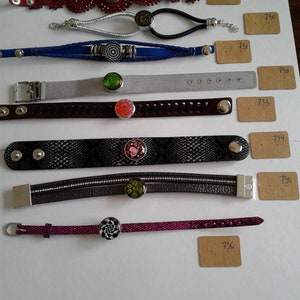 May include: A collection of 10 bracelets with different coloured leather straps, metal chains, and decorative charms. Each bracelet has a unique design and features a colourful glass button.