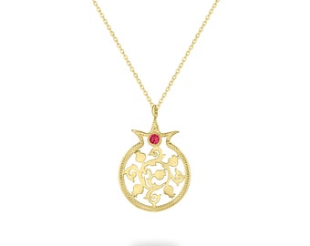 Peut inclure: Un collier pendentif doré avec un motif de grenade. Le pendentif est orné d'une pierre rouge et de motifs floraux détaillés. La chaîne dorée fine met en valeur ce bijou élégant.