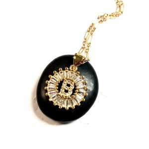 May include: Gold necklace with a pendant featuring the letter B surrounded by clear cubic zirconia stones.