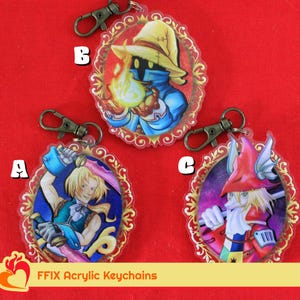 Può includere: Tre portachiavi in acrilico colorati con personaggi della serie di videogiochi Final Fantasy. Ogni portachiavi ha una forma ovale con una cornice dorata e un personaggio al centro. Il primo portachiavi presenta un personaggio con un cappello blu e un abito blu e bianco. Il secondo portachiavi presenta un personaggio con un cappello rosso e un abito rosso e bianco. Il terzo portachiavi presenta un personaggio con un cappello giallo e un abito blu e bianco. I portachiavi sono etichettati con A, B e C.