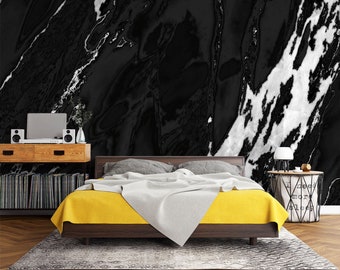 May include: A yellow bedspread with a white blanket on top of a bed with a black and white marble patterned headboard. The bed is in a room with a wooden floor and a side table with a lamp.