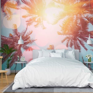 May include: A white bed with white bedding and pillows in a bedroom with a tropical palm tree mural on the wall. The mural features a sunset sky with pink, orange, and blue hues.