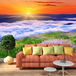 May include: A red striped couch with yellow, green, and brown throw pillows sits in front of a scenic mural depicting a mountain range with a sunrise over a sea of clouds.