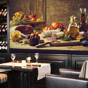 May include: A still life featuring a wooden table laden with Italian food. The table displays tomatoes, salami, olives, oil, and a bottle of wine. A wine rack and a table set for two are in the foreground.