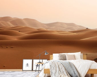 May include: A panoramic view of a desert landscape with rolling sand dunes. The dunes are a warm orange color and extend to the horizon. The sky is a soft pink and orange color.