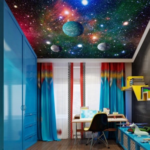 May include: A child's bedroom with a blue closet, a desk with a chair, and a ceiling painted with a galaxy scene. The ceiling features stars, planets, and nebulae in shades of blue, red, and purple.