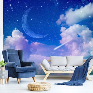 May include: A blue armchair and a white sofa with a blue throw blanket are positioned in front of a wall mural depicting a night sky with a crescent moon, clouds, and stars.