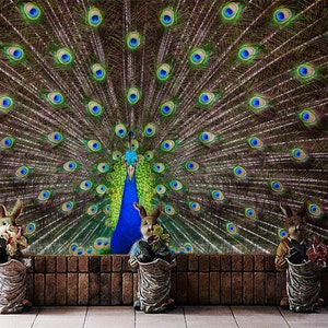 May include: Three brown rabbit figurines with green leaves in their paws stand in front of a peacock with its feathers spread out in a fan shape. The peacock's feathers are blue, green, and brown. The background is a brick wall.