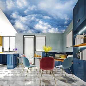 May include: A modern dining room with a blue and white cloud-themed ceiling. The room features a round glass table, colorful chairs, and built-in blue cabinets. The floor has a geometric pattern, and the kitchen area is visible.