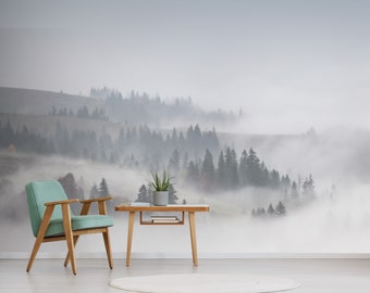 May include: A teal armchair with wooden legs sits in front of a foggy mountain landscape wall mural. A small wooden table with a potted plant sits in front of the chair.