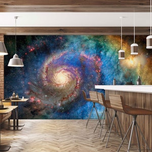 Peut inclure: Une murale de galaxie colorée avec des teintes tourbillonnantes de bleu, de vert et de jaune, avec un centre blanc brillant. La murale est affichée sur un mur dans un décor de bar moderne avec des tabourets et des tables en bois.