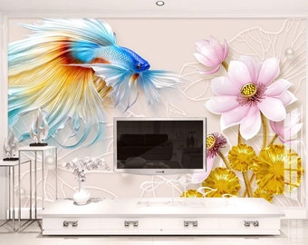 Könnte beinhalten: Eine Wandmalerei mit einem bunten Fisch mit blauen, gelben und roten Schuppen und rosa und goldenen Lotusblumen. Die Wandmalerei ist an einer Wand mit einem Fernseher und einem weißen Regal angebracht.