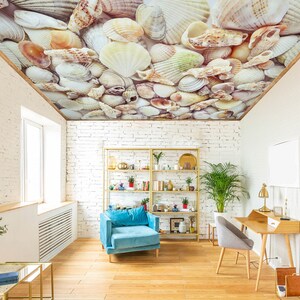 Könnte beinhalten: Ein Wohnzimmer mit einer weißen Backsteinwand, einem blauen Sessel, einem Holzschreibtisch mit Stuhl, einem Bücherregal und einer Decke, die mit einem Muschelmuster bedeckt ist.